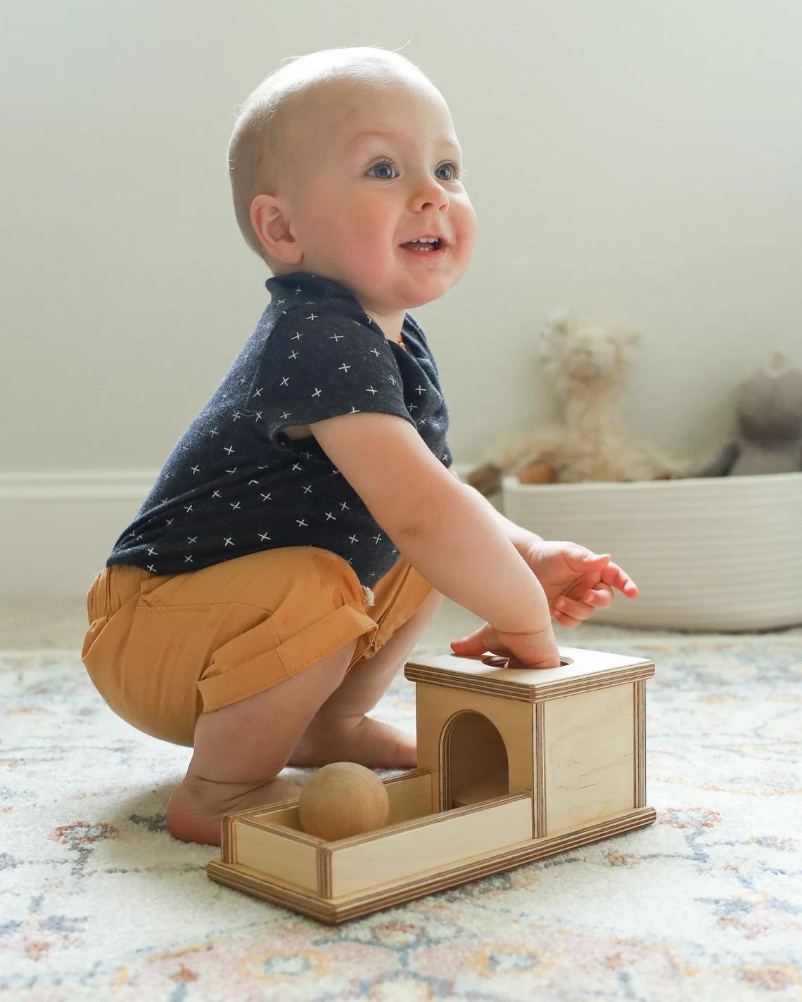 A baby playing with a wooden object permanence box